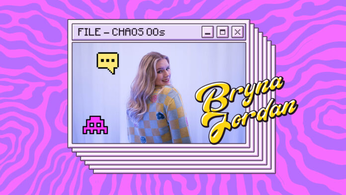 A photograph of CHAOS Radio presenter Bryna Jordan. She is wearing a grey and yellow checked jumper, with flower and smiley face motifs intermittently showing.