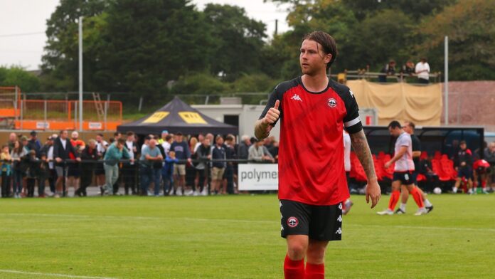 CHAOS Radio Newswave - Truo City player on the pitch, in uniform/kit, with many viewers and fans behind a barrier in the background.